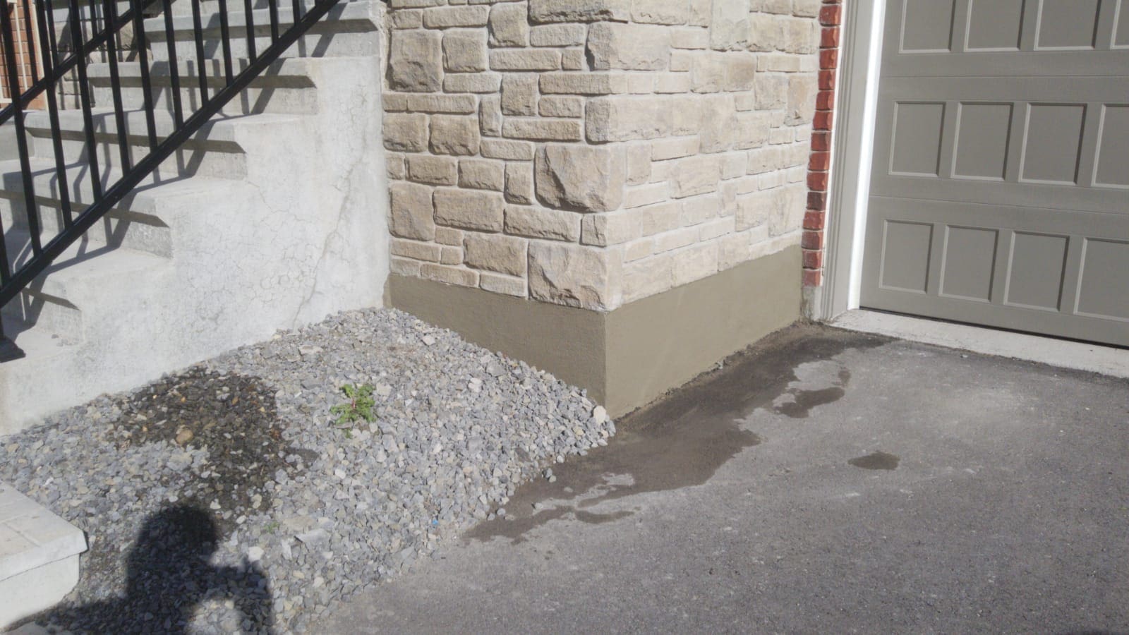 Freshly resurfaced concrete on the bottom of the exterior wall between a deck staircase and the garage