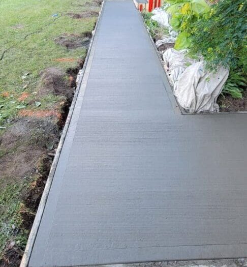 Freshly poured concrete walkway alongside a house