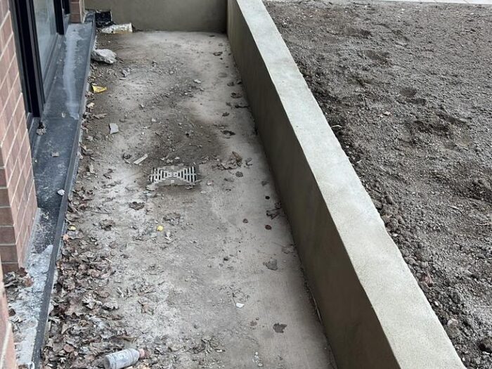 Formed concrete retaining wall beside a driveway