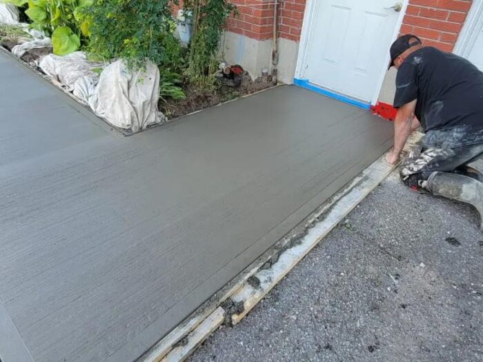 Freshly poured concrete walkway beside a gravel bed