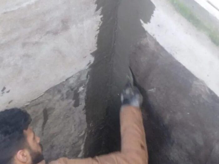 Hand-applying waterproofing to an exposed wall