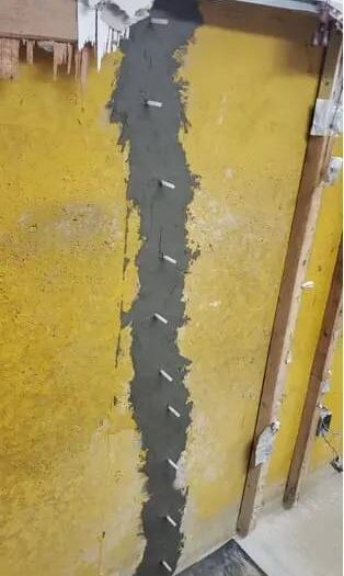 Injection ports set along a foundation crack, resin going in