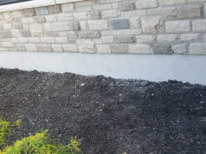 Stone retaining wall built above a new concrete strip