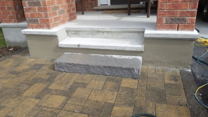 Parged foundation and porch step beside an interlock walkway