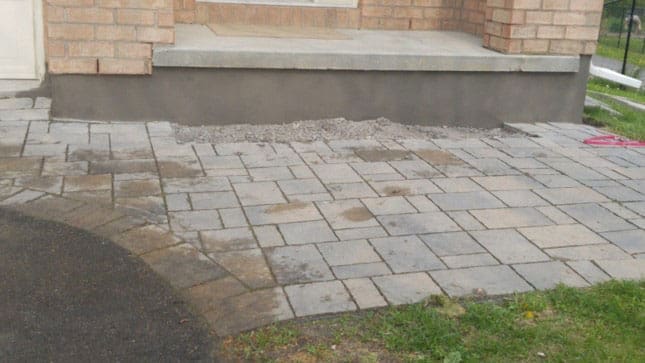 Parged foundation wall running alongside a stone patio