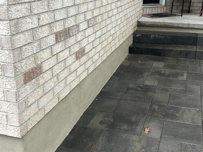 Parged foundation running the length of a side walkway