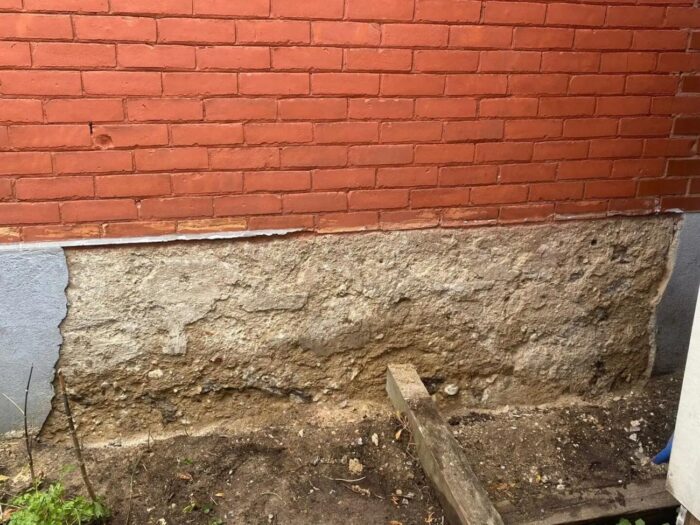 Parged foundation below brick, edged to the paving