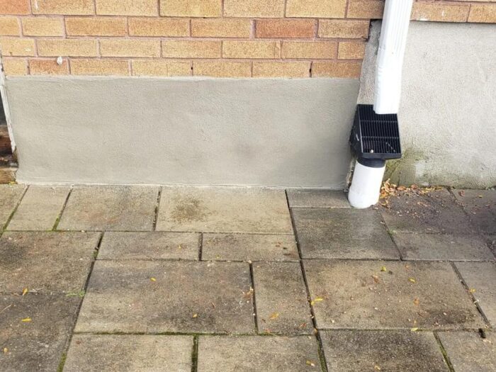 Parged foundation strip along a red brick wall