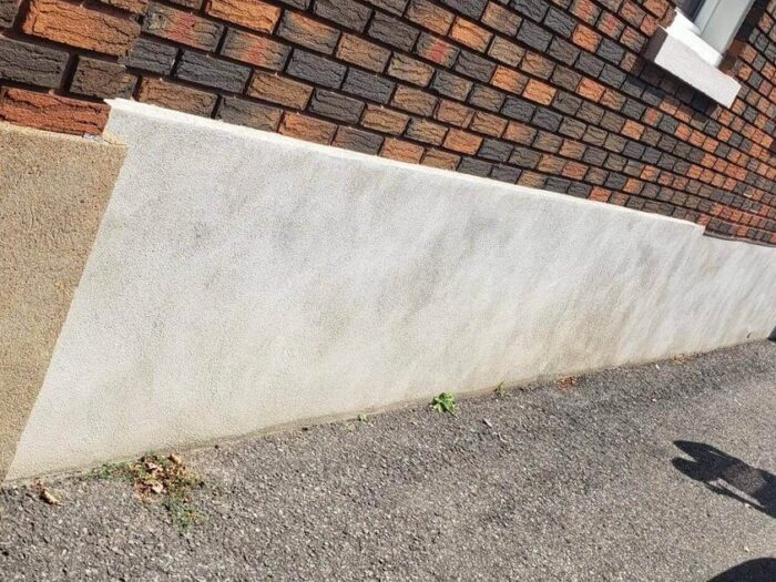Fresh parging along the base of a rendered wall