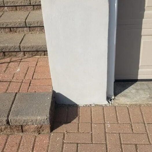 Parged foundation corner beside a stone step