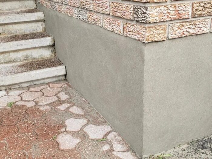 Parged foundation wall beside a flagstone path
