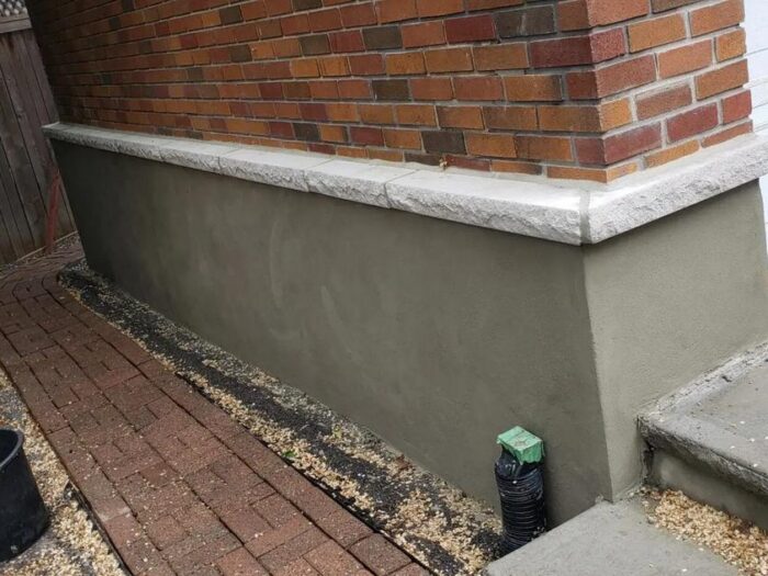 Parged foundation running along a driveway edge