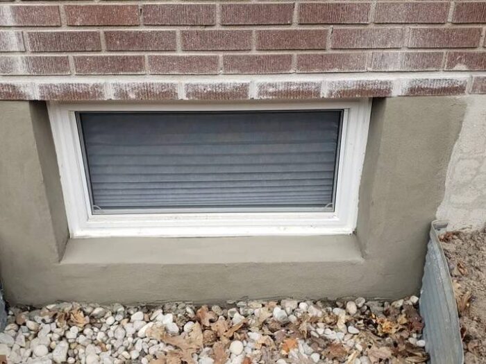 Parged foundation corner, edged clean to the paving