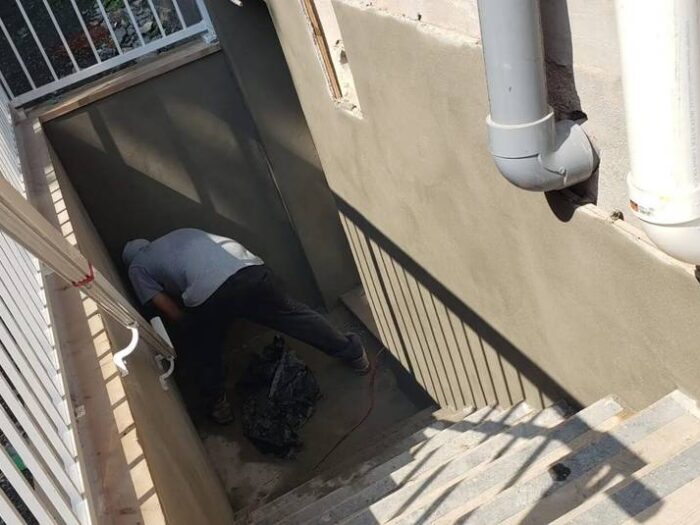 Working the parging coat in behind a downpipe