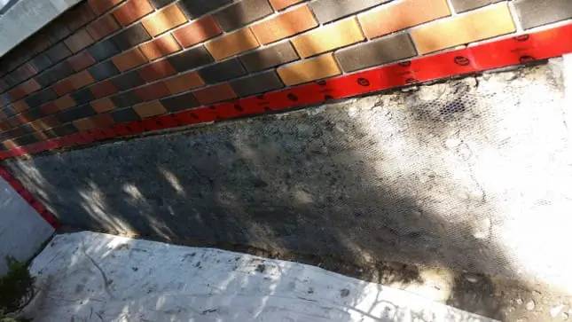 Parged foundation below a stone facade